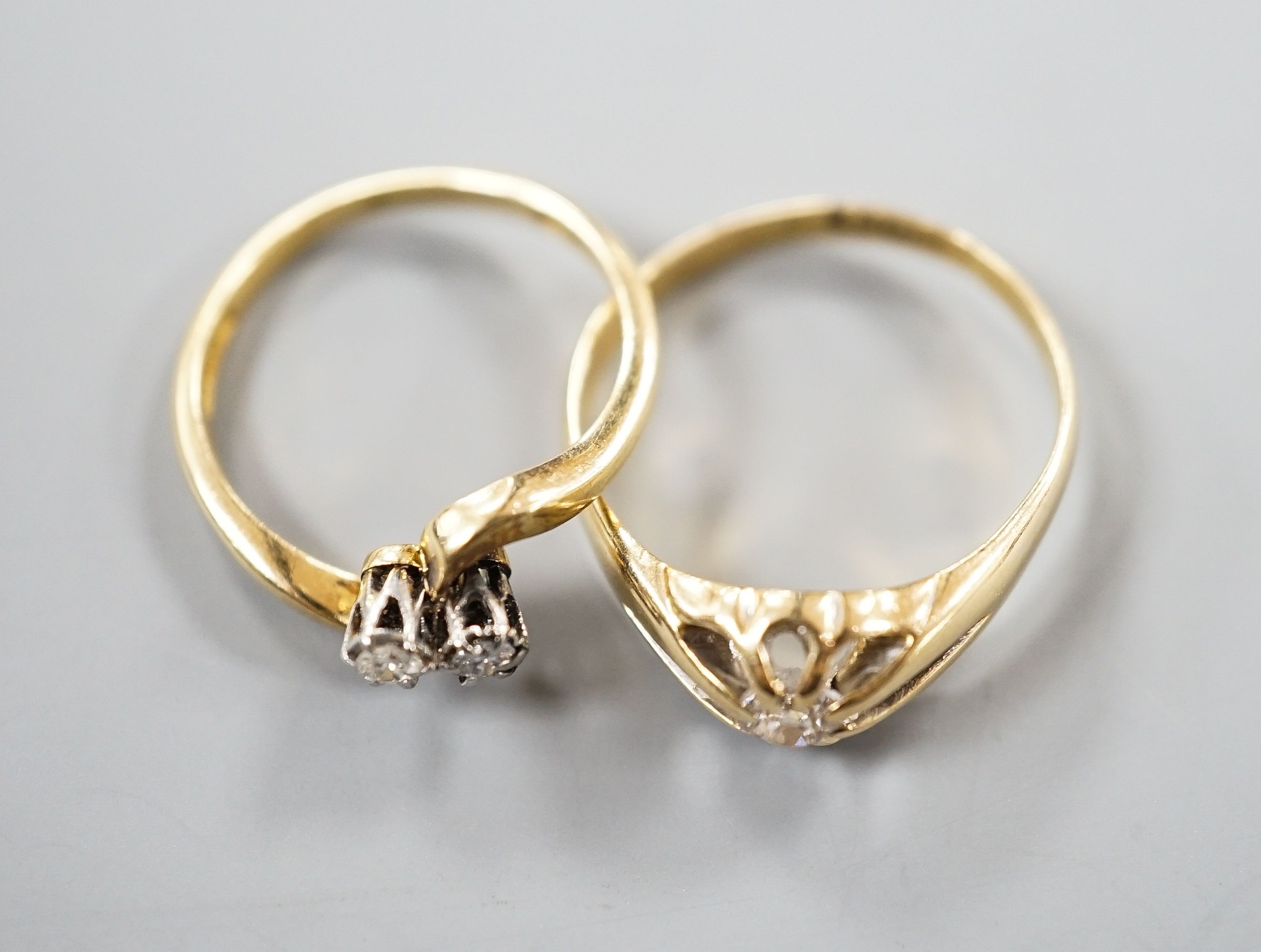 An early 20th century 18ct gold and claw set solitaire diamond ring, size O and an 18ct & Pt, two stone diamond set crossover ring, size K, gross weight 5.7 grams.